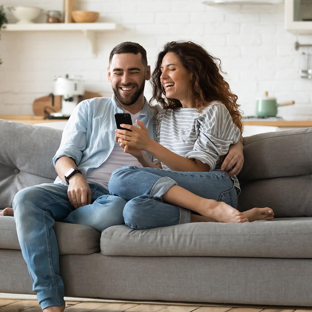 couple smiling at phone after being accepted for a loan