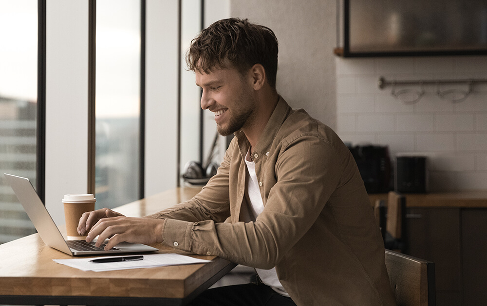 man types on computer smiling