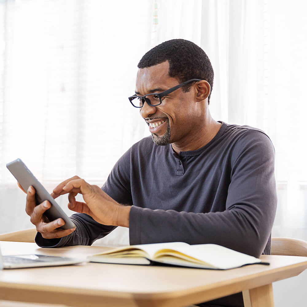 man with book smiles at phone