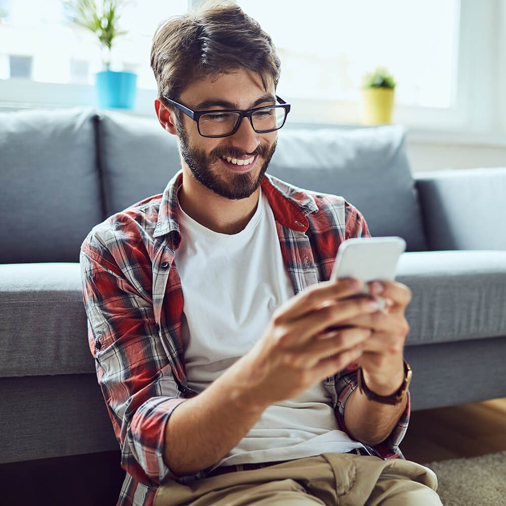 young man leaning against sofa on phone