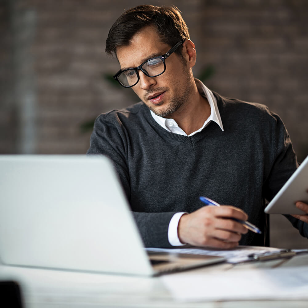 man with notebook reading laptop