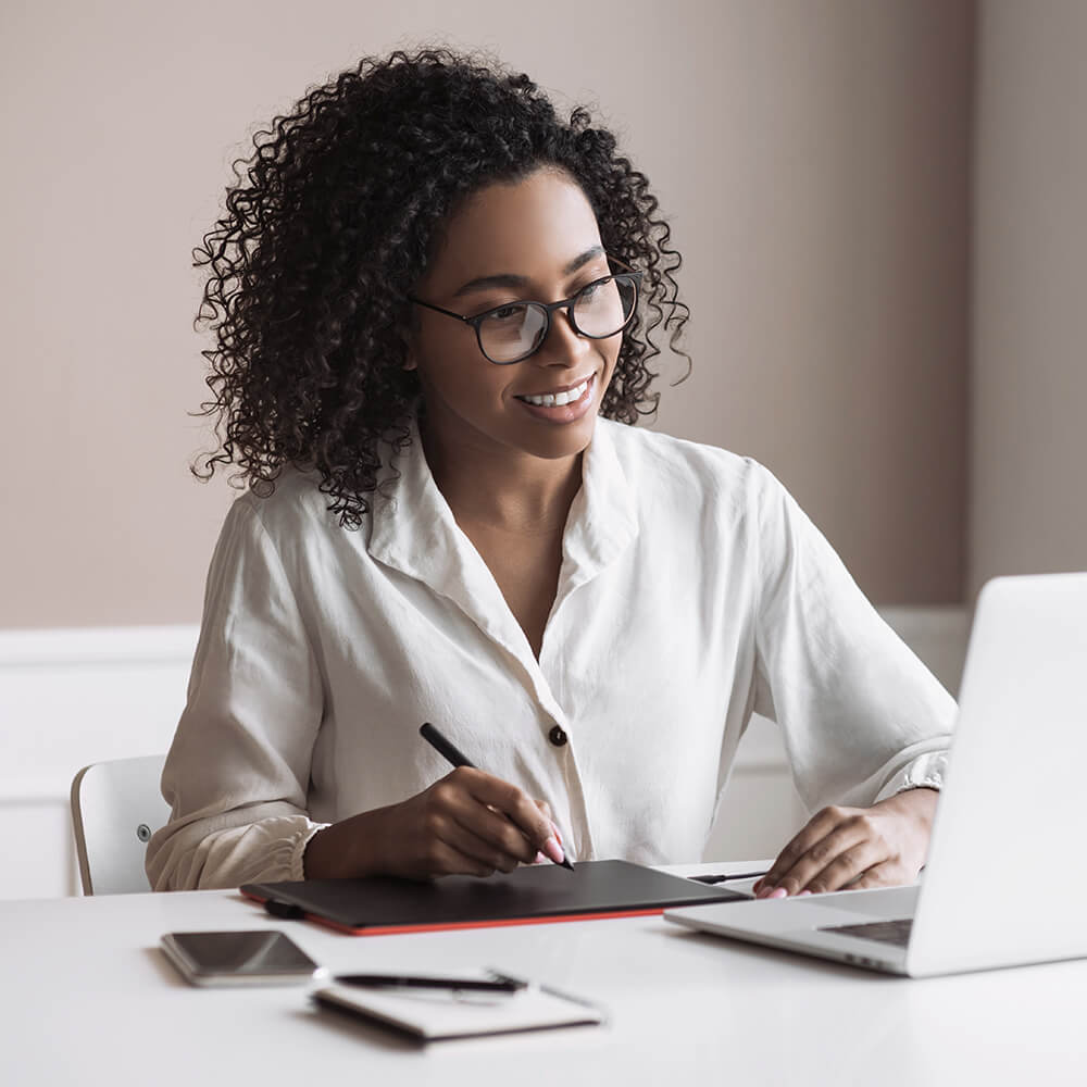 women writing notes on tablet from laptop
