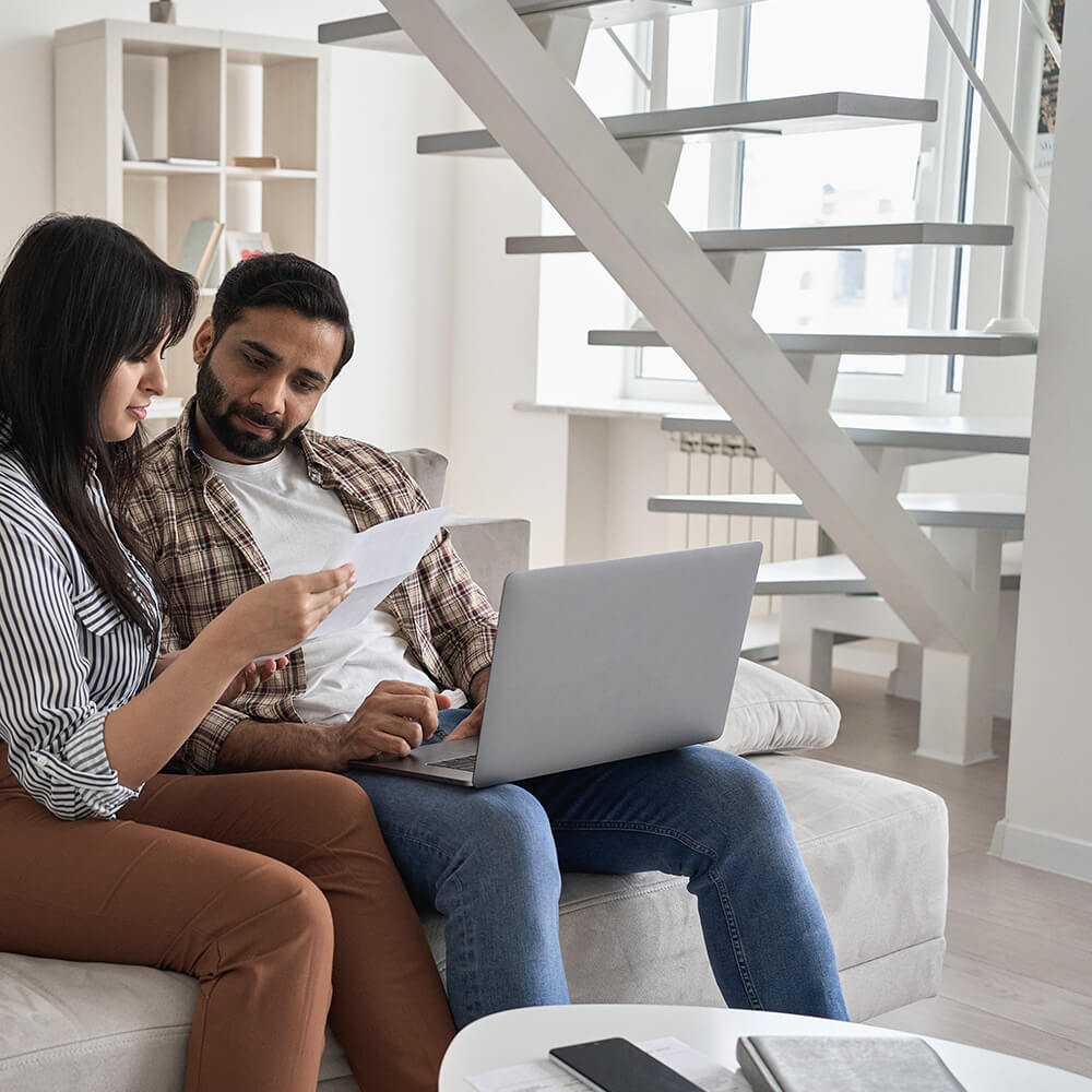 couple reading over paper on sofa