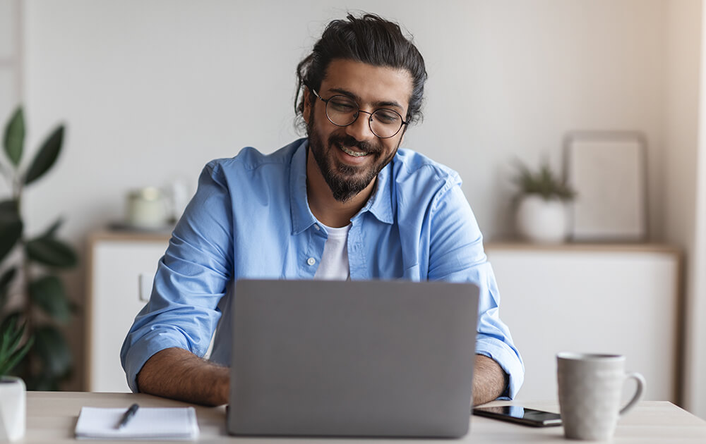 man in glasses smiling st laptop