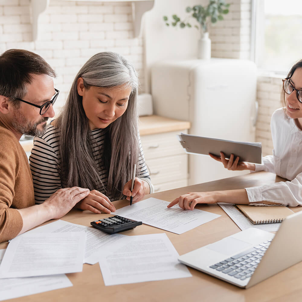 couple and financial adviser go over notes with a calculator