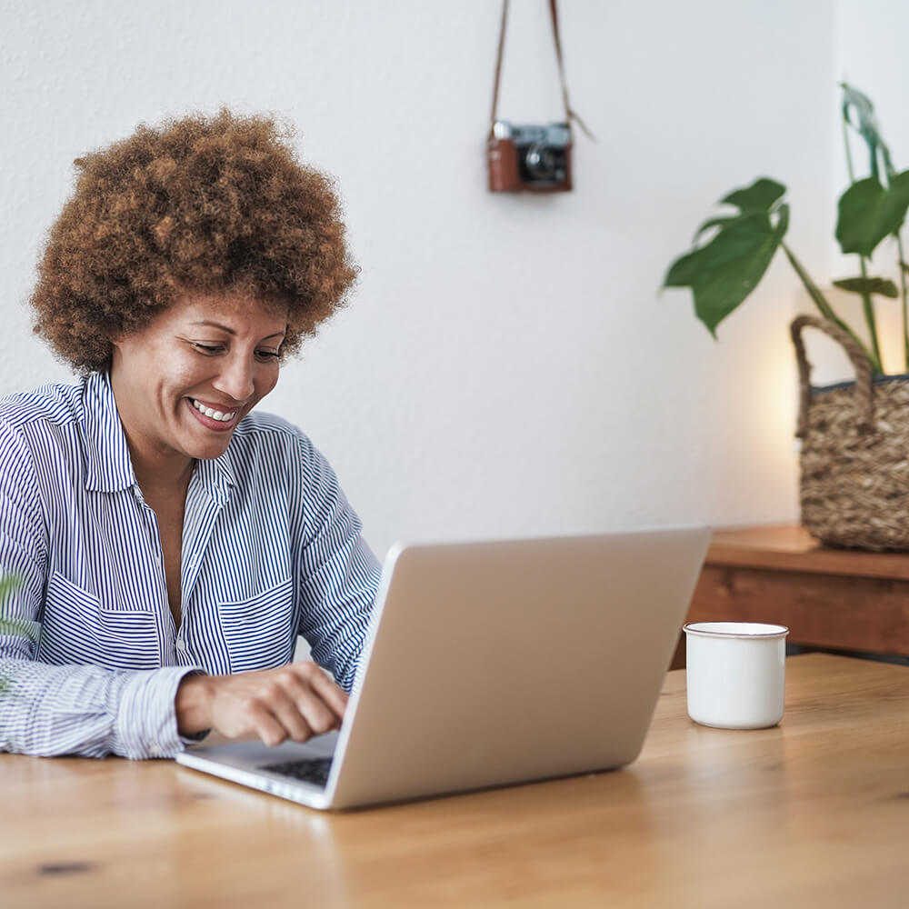 older woman smiling at her computer at table