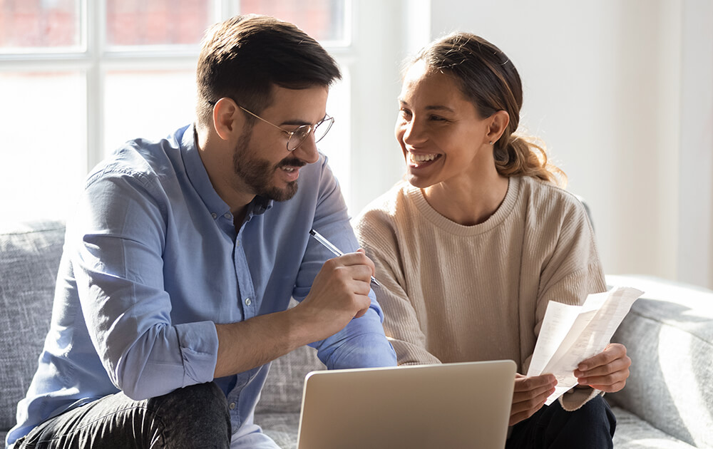 couple smiling at laptop and papers