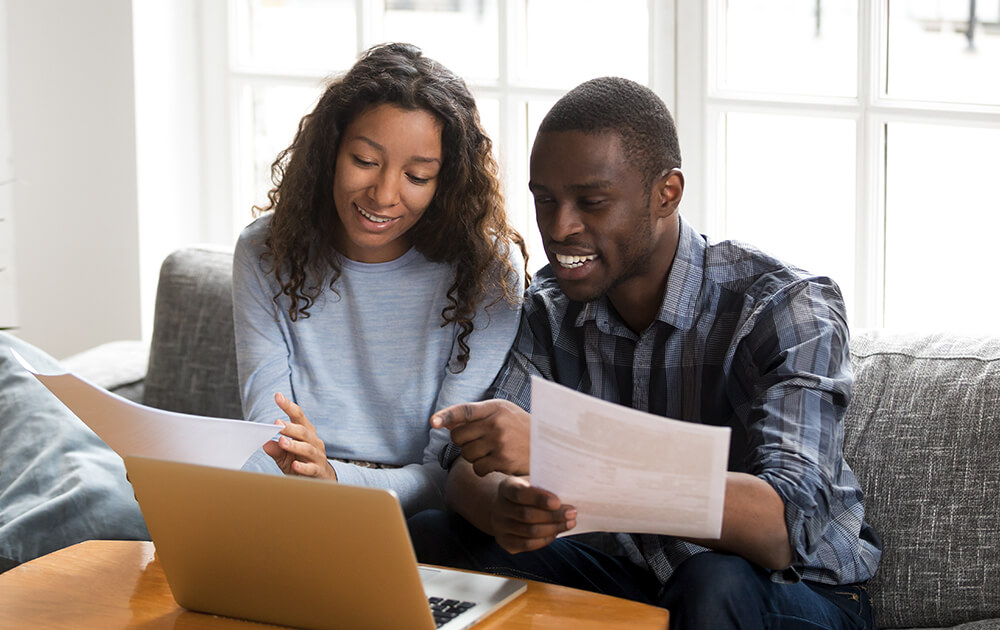 couple smiling while reading over papers