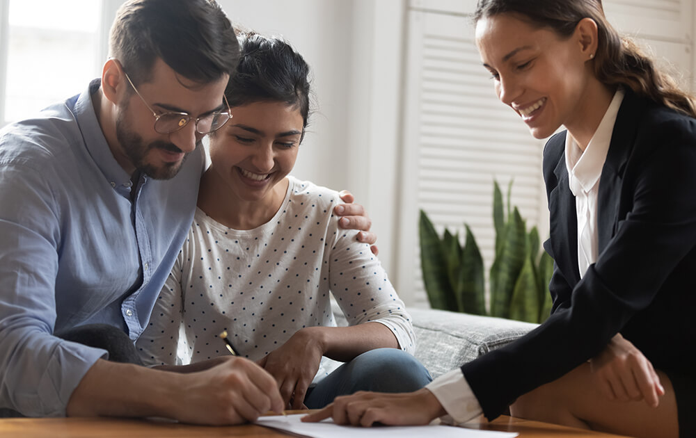 couple smiling and holding each other while signing papers