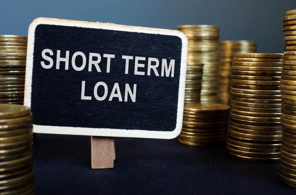 A sign saying short term loan surrounded by stacks of coins
